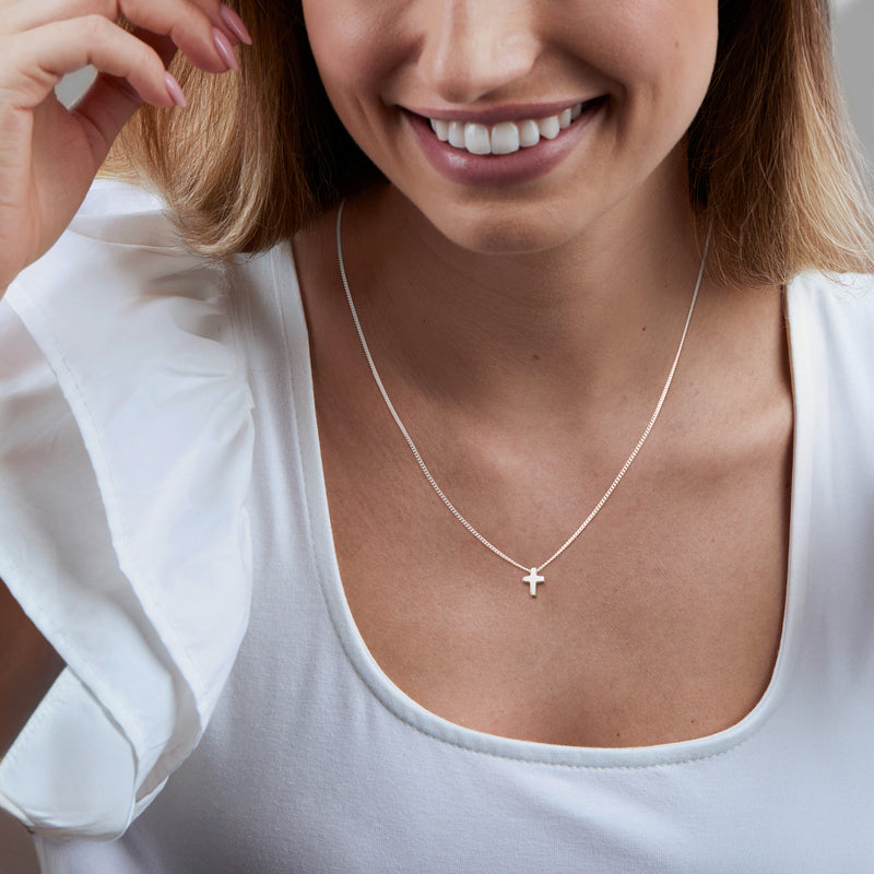 Sterling silver mini cross pendant necklace on a woman, small cross on thin chain
