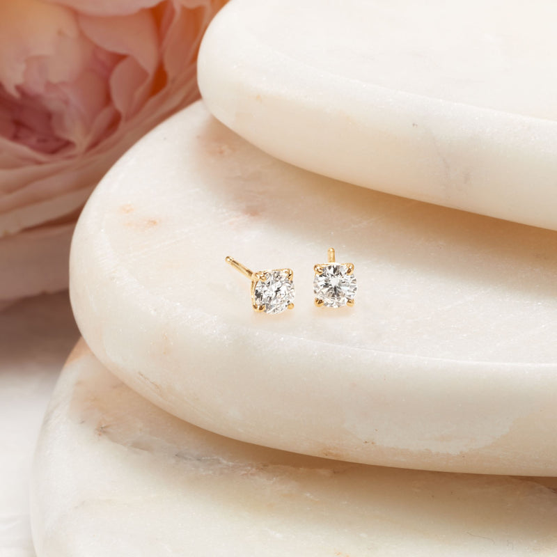 Close-up of 14kt yellow gold diamond stud earrings with round bezel-set stones