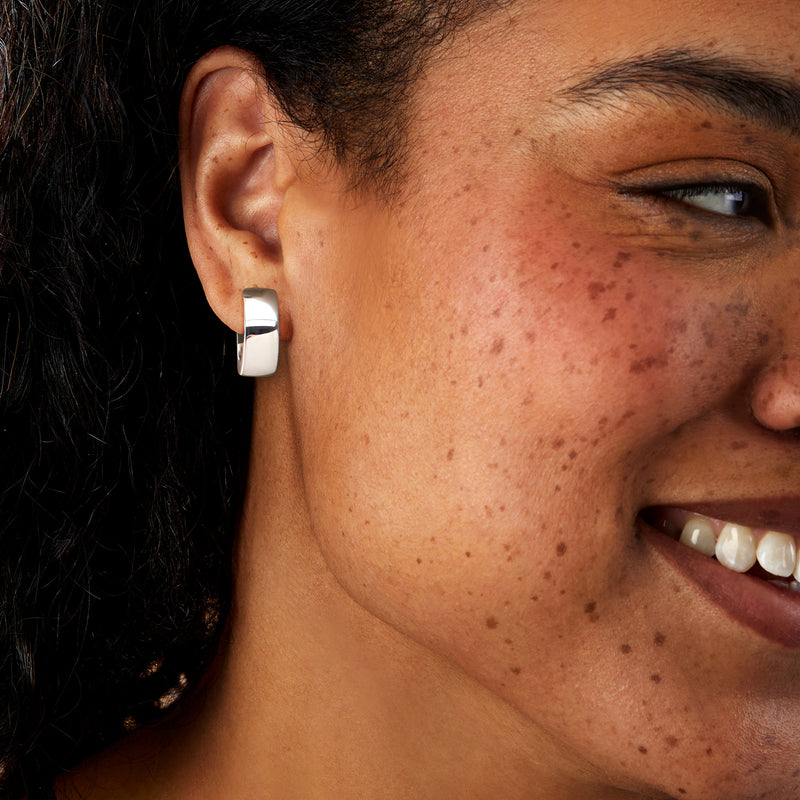 Model wearing sterling silver clip-on hoop earrings with hinged clasp, polished silver