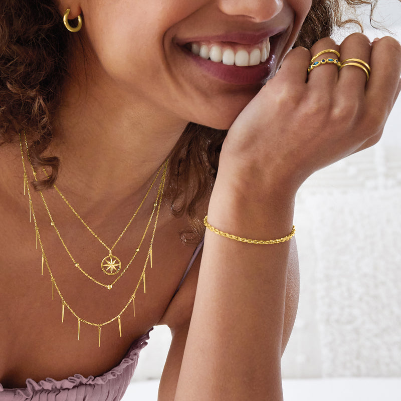14kt yellow gold huggie hoop earring on ear, close-up