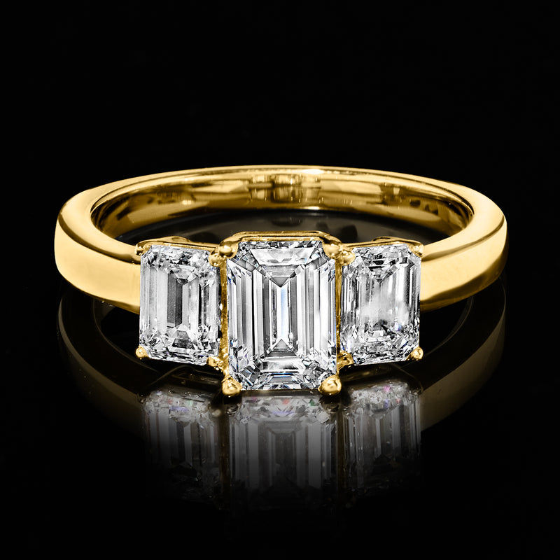 Three-stone emerald-cut diamond ring in 14kt yellow gold, top view with sparkle