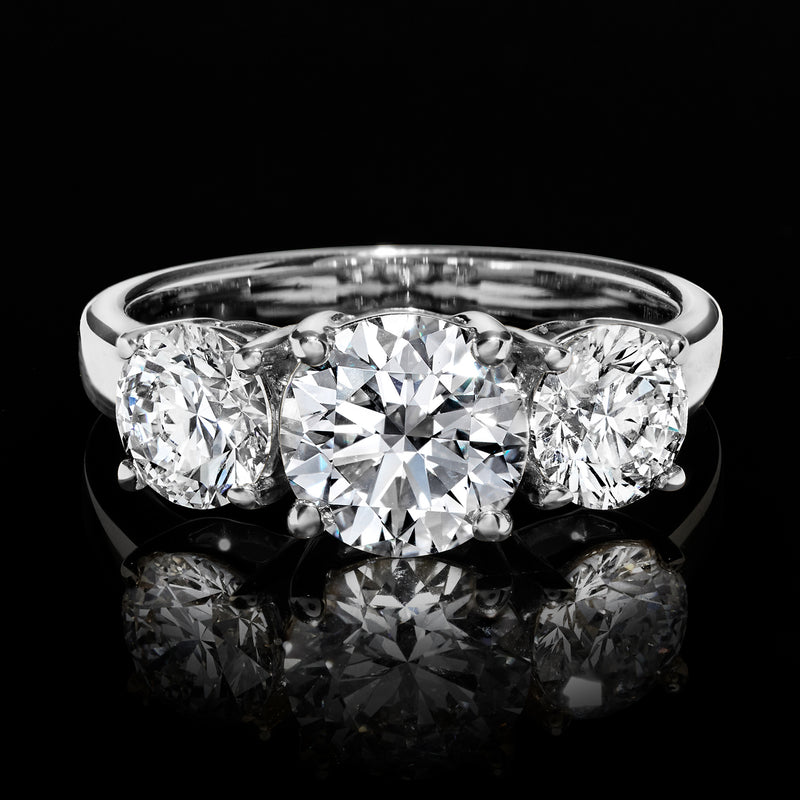 Three-stone diamond ring with round center stone and two round side diamonds, white gold