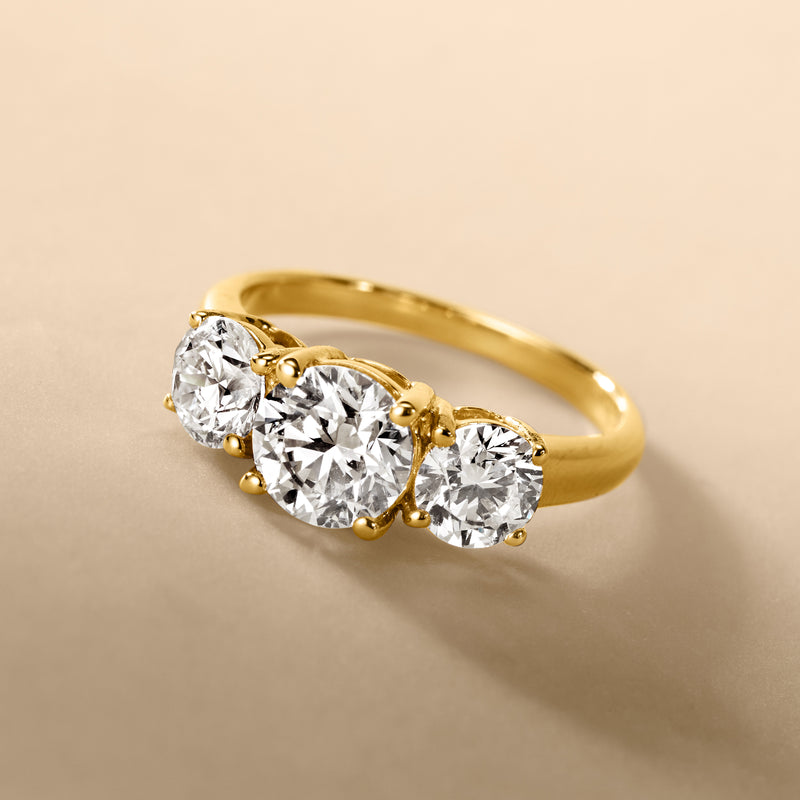 Round lab-grown diamond three-stone ring in 14kt yellow gold, angled view