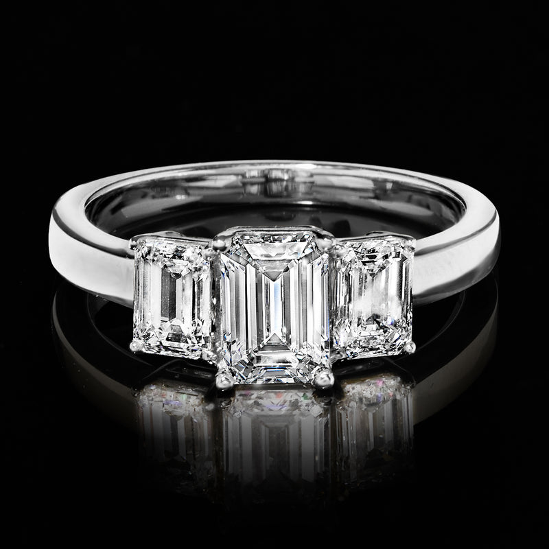 14kt white gold three-stone emerald-cut diamond ring, front view with side diamonds.