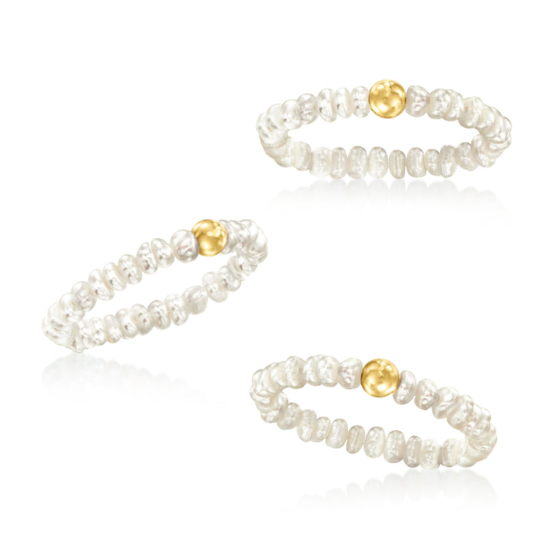 Three cultured pearl stretch rings with yellow gold domes, laid out