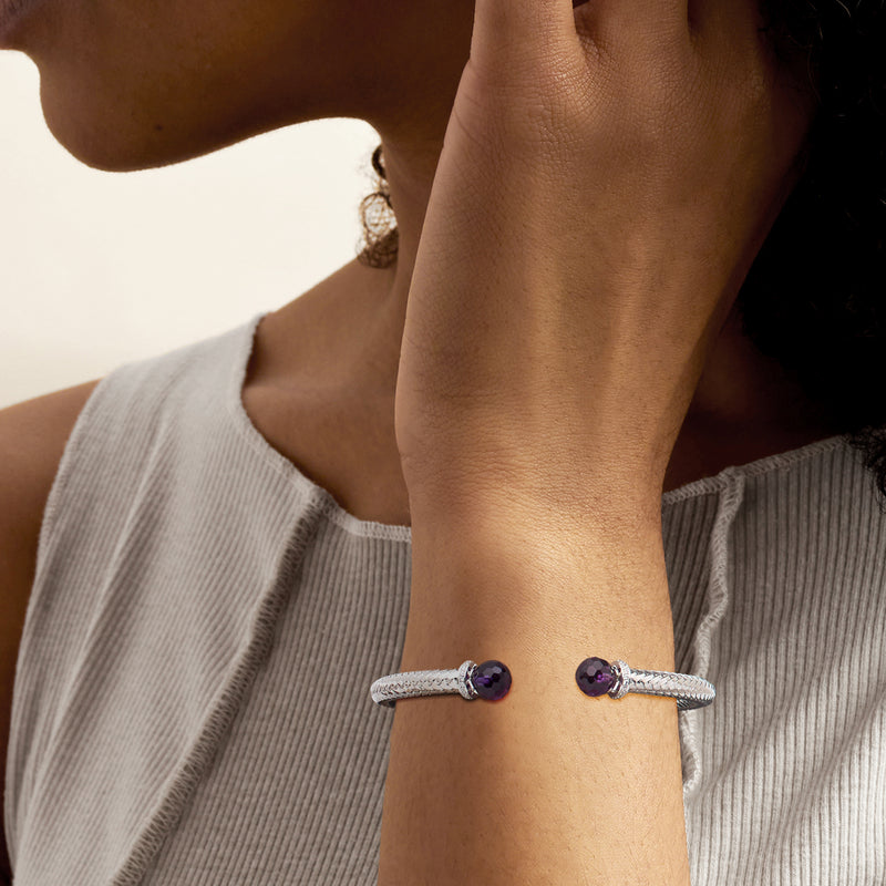 Sterling silver cuff bracelet worn on wrist with two round purple stones