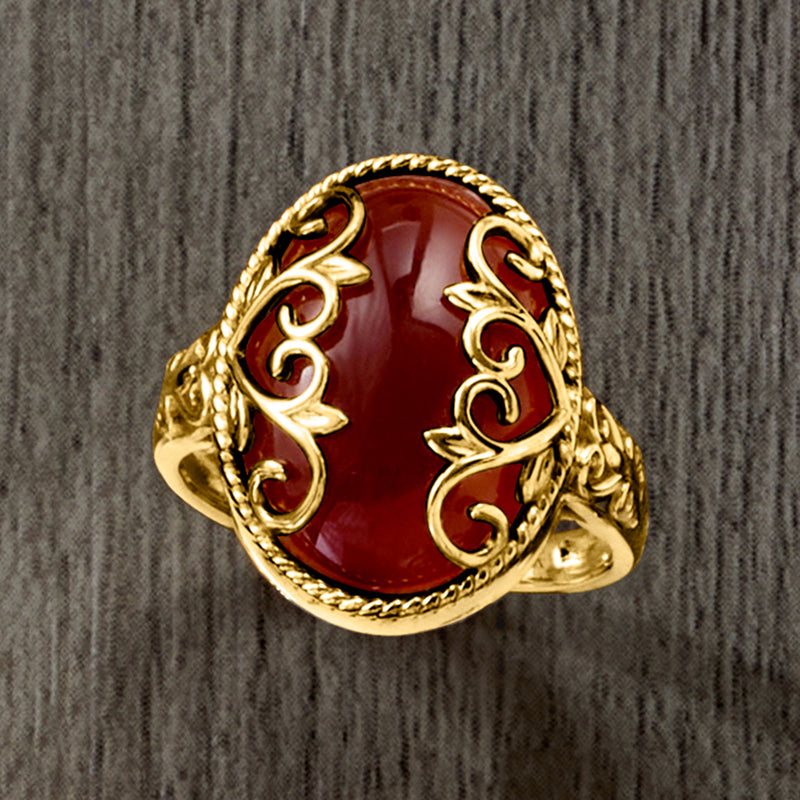 Red oval agate ring with ornate gold heart scrolls and textured halo band