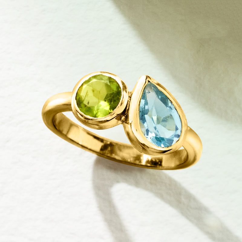 Gold toi et moi ring with green peridot and blue topaz stones, one on each side