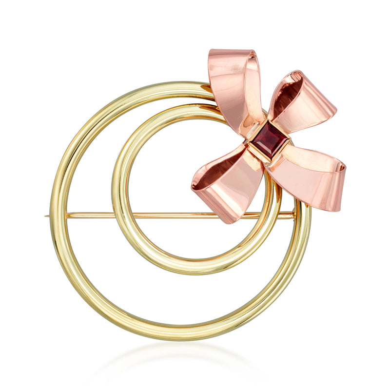 Two-tone gold bow and circle pin with red gemstone detail