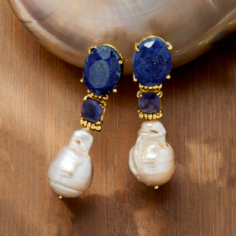 Gold drop earrings close-up: dark blue stones with baroque white pearl drops