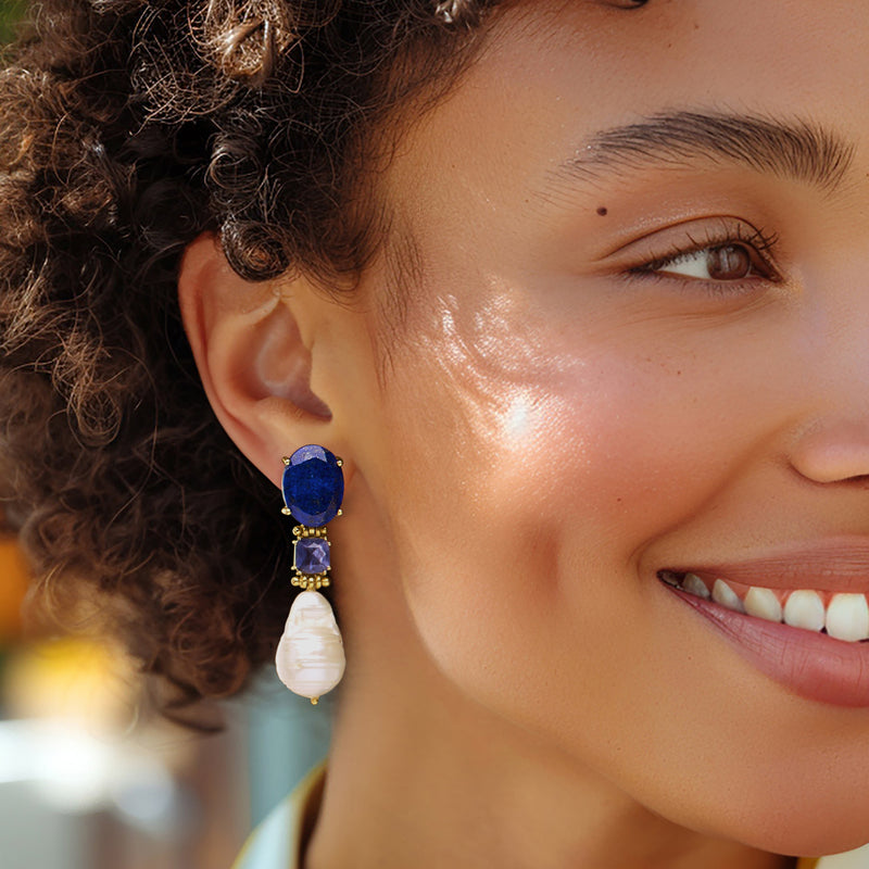 Baroque pearl drop earrings on model, with gold settings and dark blue stones