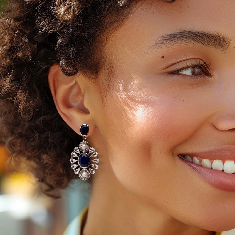 Sterling silver drop earring with dark blue center stone, white pearl drop, and clear halo