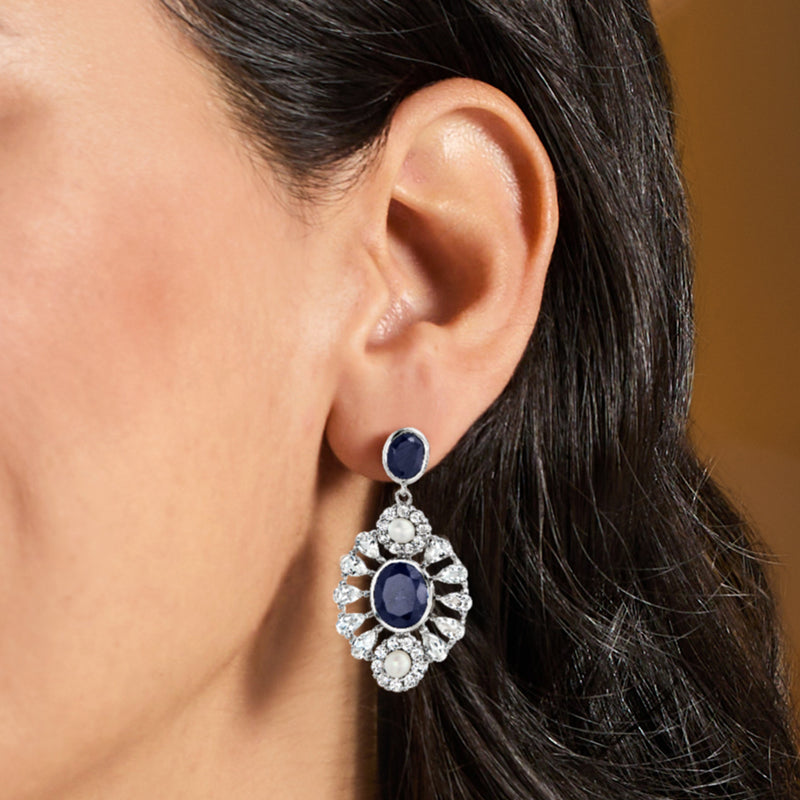 Sterling silver drop earring with dark blue center stone and white pearl accents in clear halo