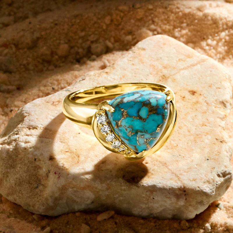 Turquoise gemstone ring in gold with diamond side accents, angled view
