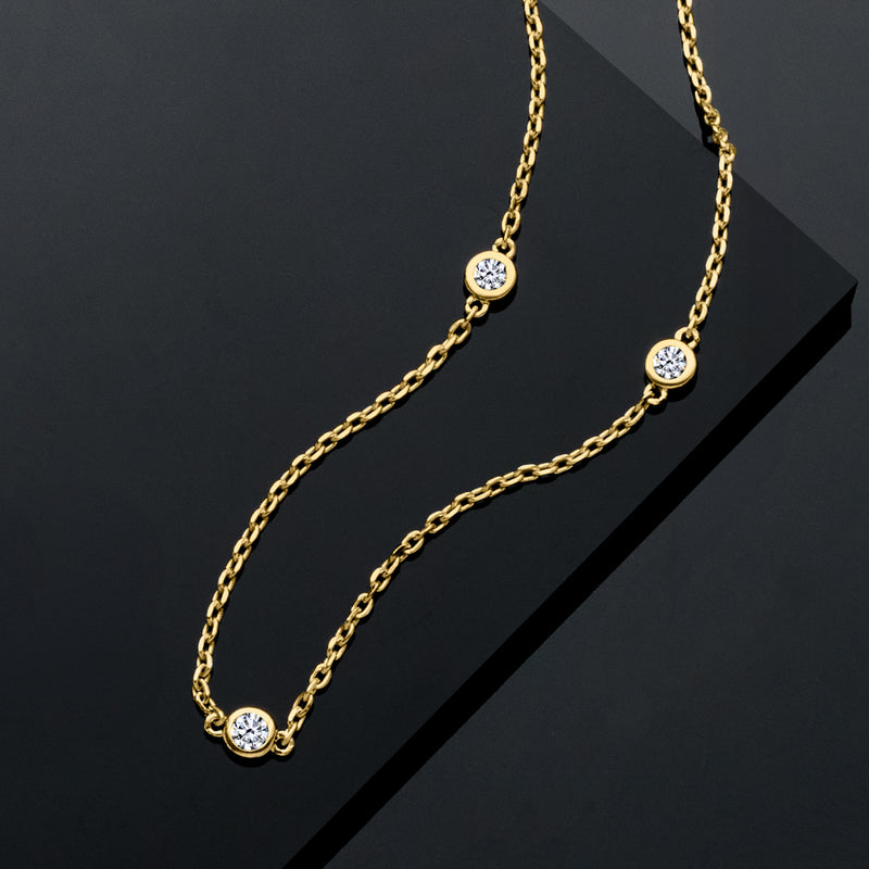 Gold station necklace with round diamond stations on a textured link chain