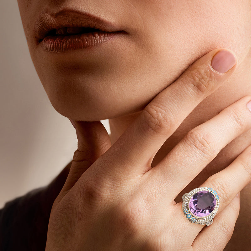 Vintage amethyst ring on finger, oval purple stone with blue enamel and pearl border