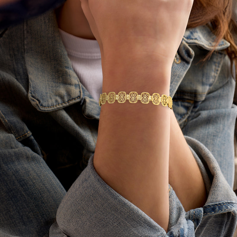 Gold filigree bracelet worn on wrist, featuring ornate oval links