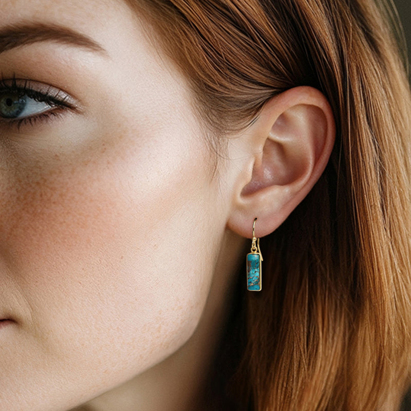 Turquoise rectangle drop earring on gold earwire, worn on model's ear