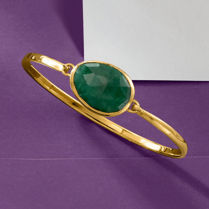 Gold oval bangle bracelet with large green gemstone centerpiece and hinge clasp