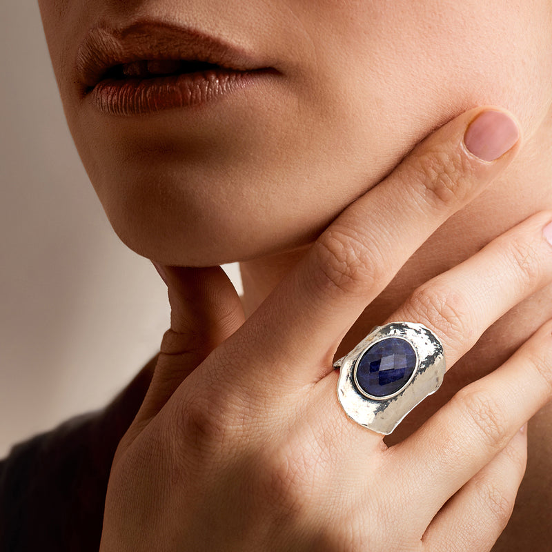 Sterling silver sapphire ring on finger, oval dark-blue gemstone close-up