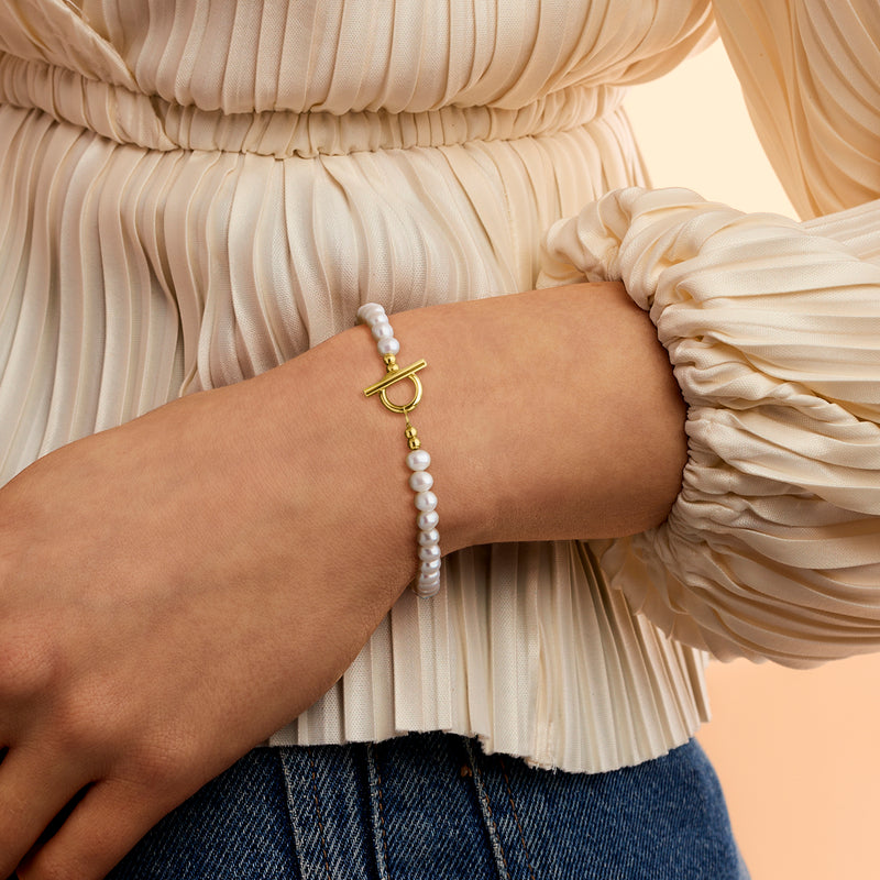 Cultured pearl bracelet with gold toggle clasp on wrist, 4–5mm pearls