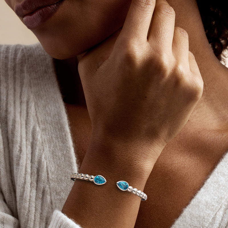 Sterling silver topaz cuff bracelet on wrist with two bright blue oval stones