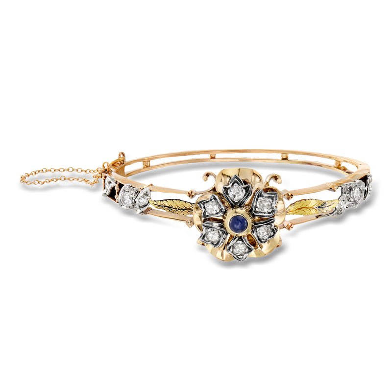 Two-tone gold bangle bracelet with blue sapphire center and diamond halo details