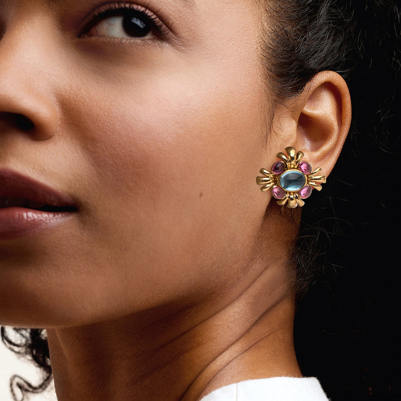Sky-blue and pink gold clip-on earrings on ear, oval center with petal-like prongs.