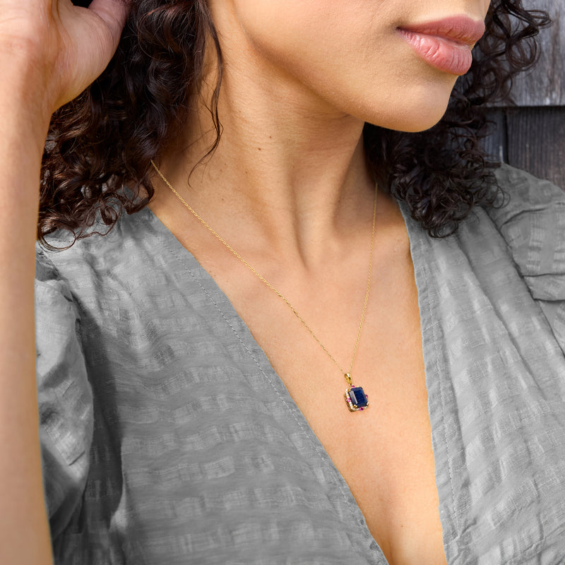 Gold pendant necklace with small square blue stone and pink-and-white accents on chain