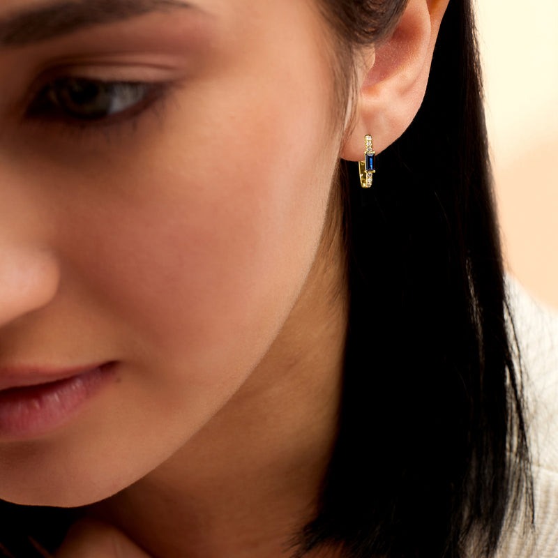 14kt yellow gold hoop earrings on ear with blue sapphire and small diamond stones