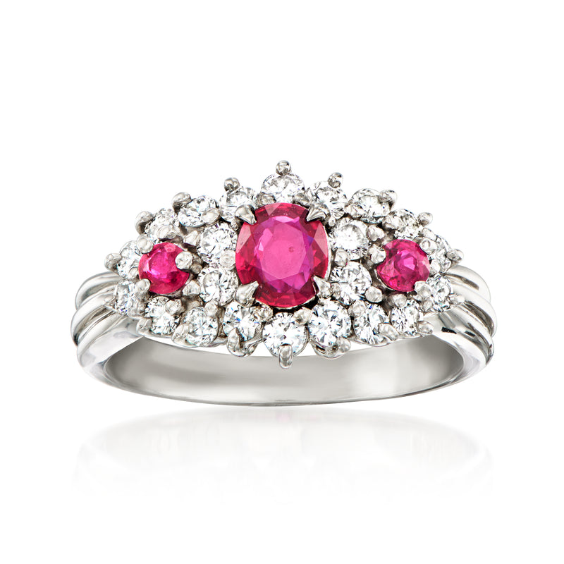 Vintage platinum ring with oval center ruby, pink ruby accents, and diamond halo