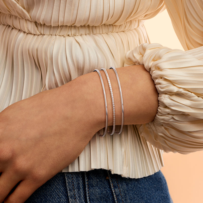 Three sterling silver bangle bracelets on wrist, two with bead texture
