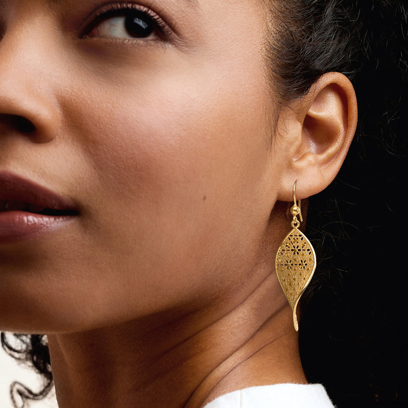 Gold-tone teardrop floral drop earrings on ear, textured lattice design with French hook