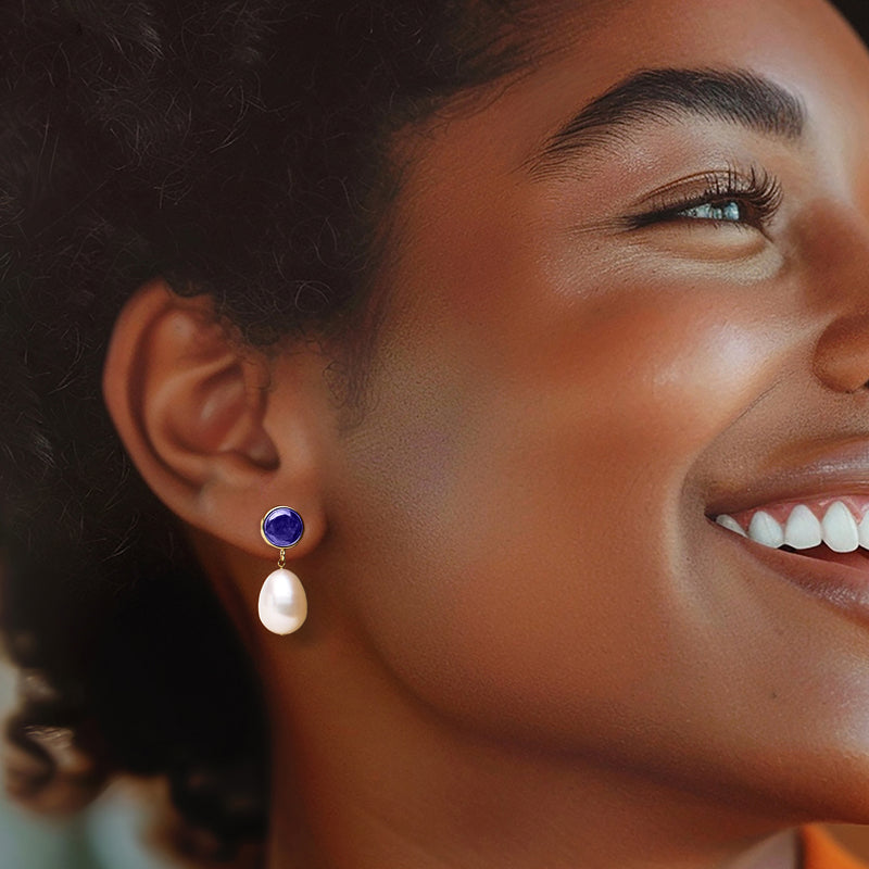 Cultured pearl drop earrings on ear: round blue sapphire with white teardrop pearl, gold