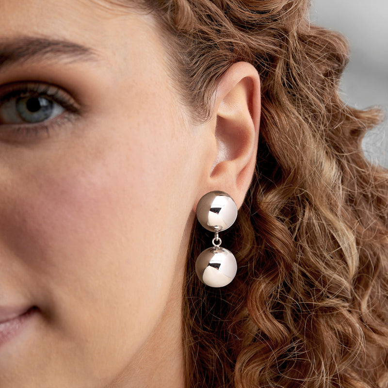 Sterling silver drop earrings with two round polished beads, worn on ear
