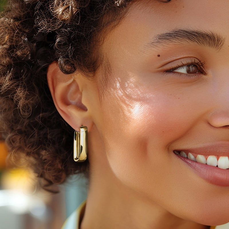 Polished yellow gold rectangular hoop earring on ear, hinged closure