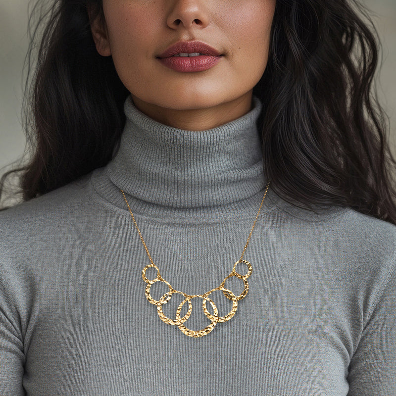 Gold-tone multi-circle necklace on a cable chain, worn with a turtleneck