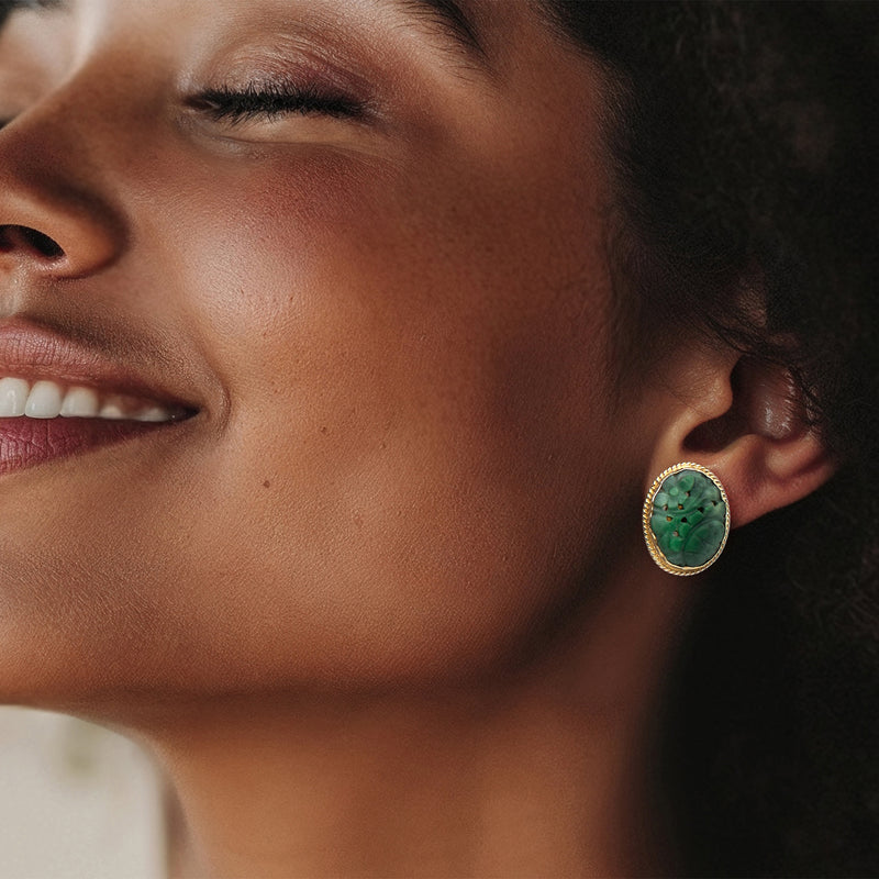 Close-up of oval carved green jade clip earring in 14kt yellow gold bezel