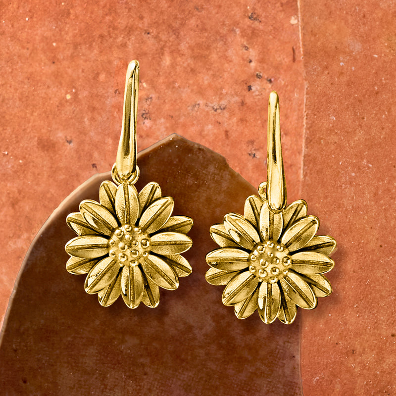 Gold daisy drop earrings with textured petals and beaded centers, dangling on ear wires