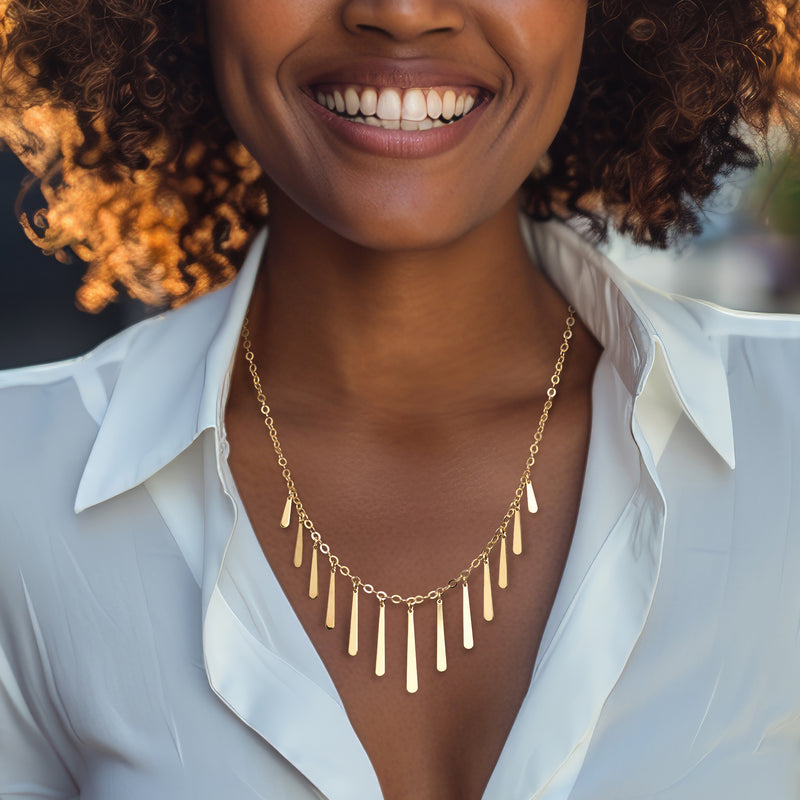 Gold teardrop fringe necklace with dangling elongated drops on a model