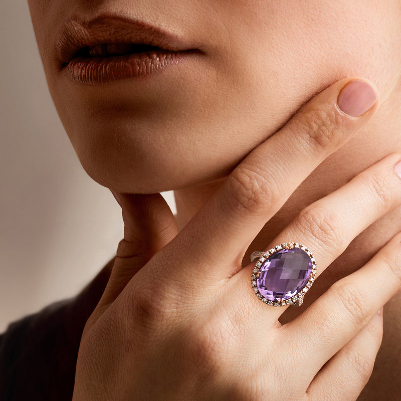 Amethyst halo ring on hand: 14kt rose gold setting with diamond border and purple center