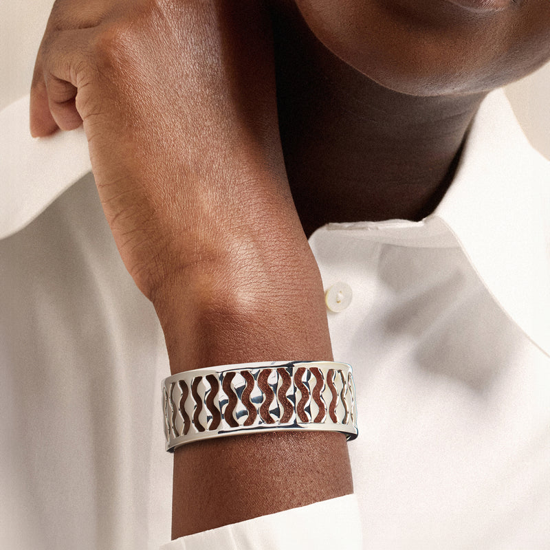 Sterling silver cuff bracelet on wrist, wave droplet cutout detail