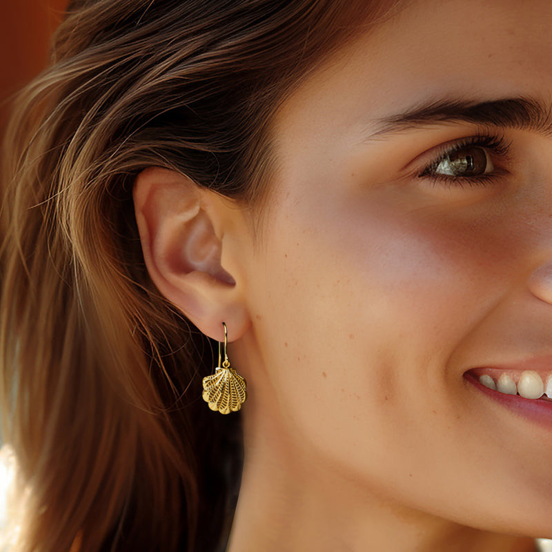 Model wearing 14kt yellow gold scallop seashell drop earrings with earwire hooks