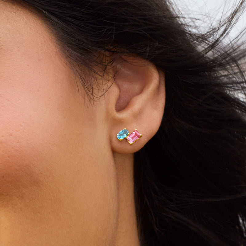 Close-up of 14kt yellow gold toi et moi studs with blue and pink topaz on ear