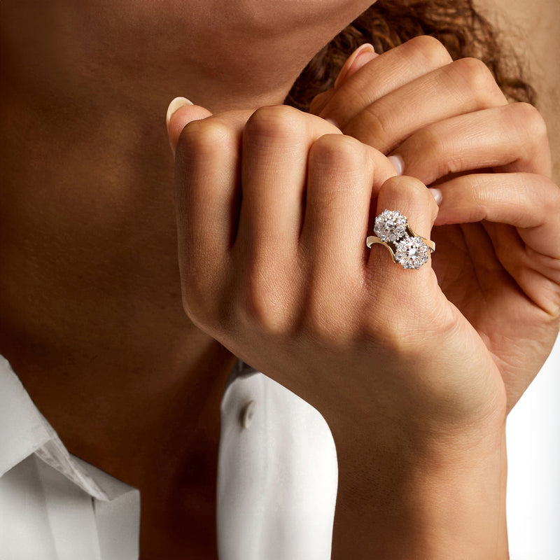 Two-tone gold diamond cluster bypass ring on hand with round sparkling centers