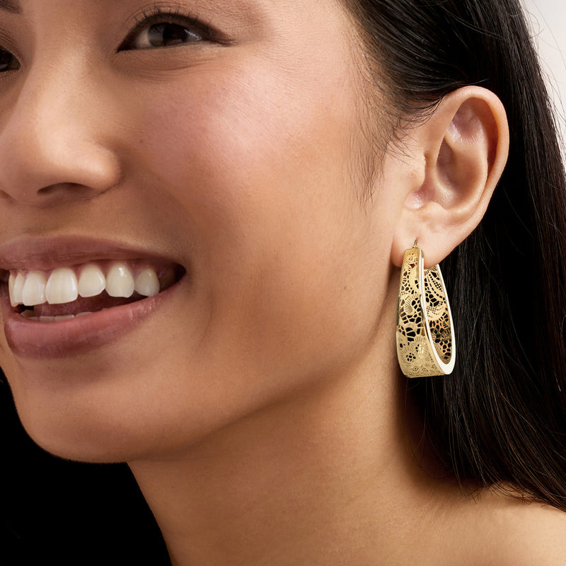 Yellow gold oval filigree hoop earrings worn, detailed floral cutouts