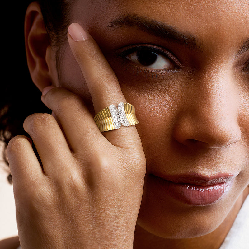 Gold ribbed diamond ring on finger with oval diamond cluster centerpiece.