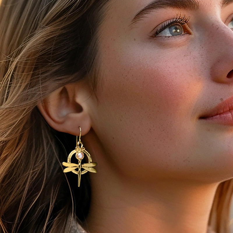 Gold dragonfly drop earrings with white pearl, dangling on earwire