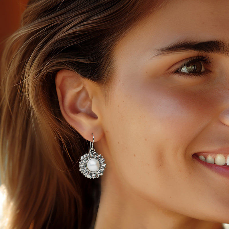 Sterling silver sunflower drop earrings with cultured pearl, worn on model with earwire