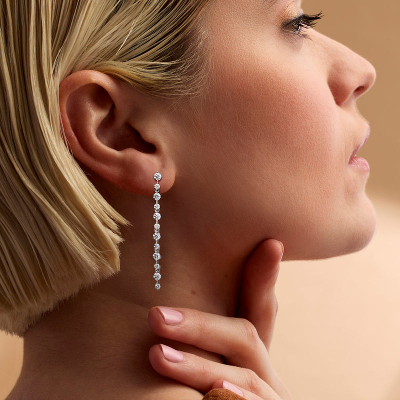 Linear drop diamond earrings in 14kt white gold, close-up on ear with row of stones